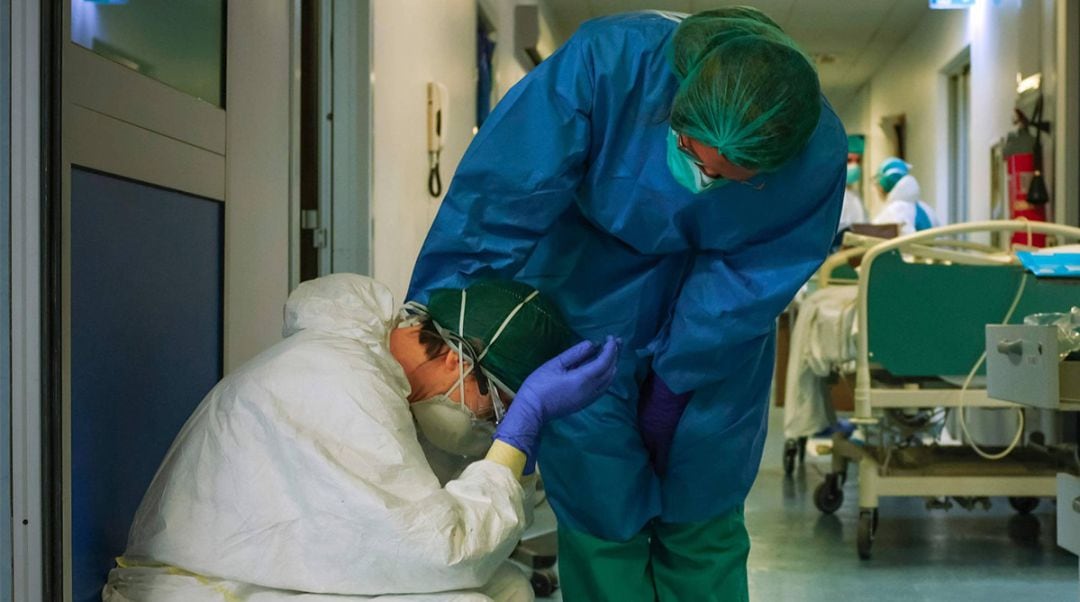 Una enfermera consuela a otra compañera en un pasillo de un hospital