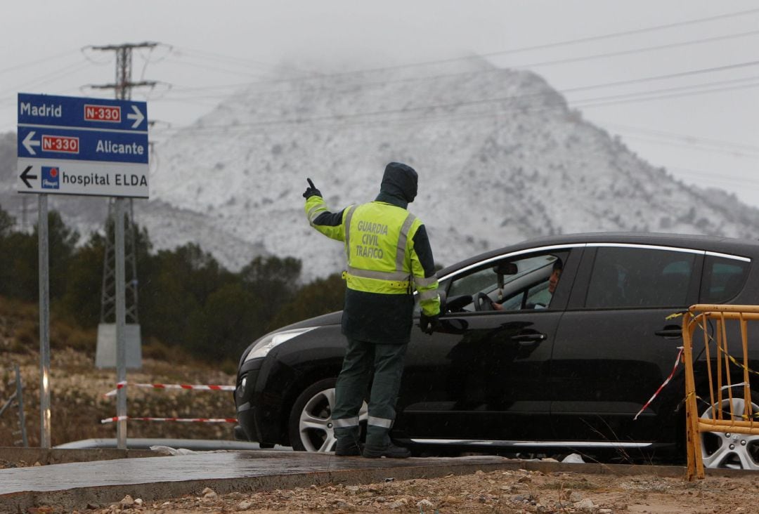 Agentes de la Guardia Civil de Tráfico indican a los conductores que la A-31 está cortada por nieve a la altura de la salida del hospital de Elda hacia Madrid.