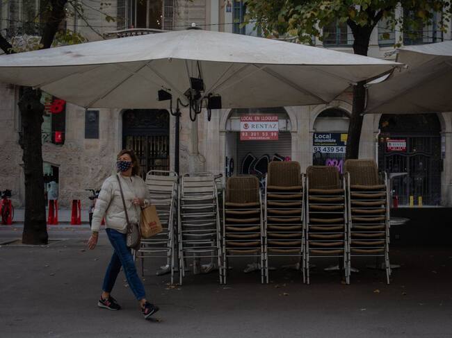 Una dona passa al costat d'una terrassa tancada d'un bar a Barcelona. La Generalitat ha prorrogat les restriccions deu dies més, a banda del toc de queda i el tancament municipal perimetral.