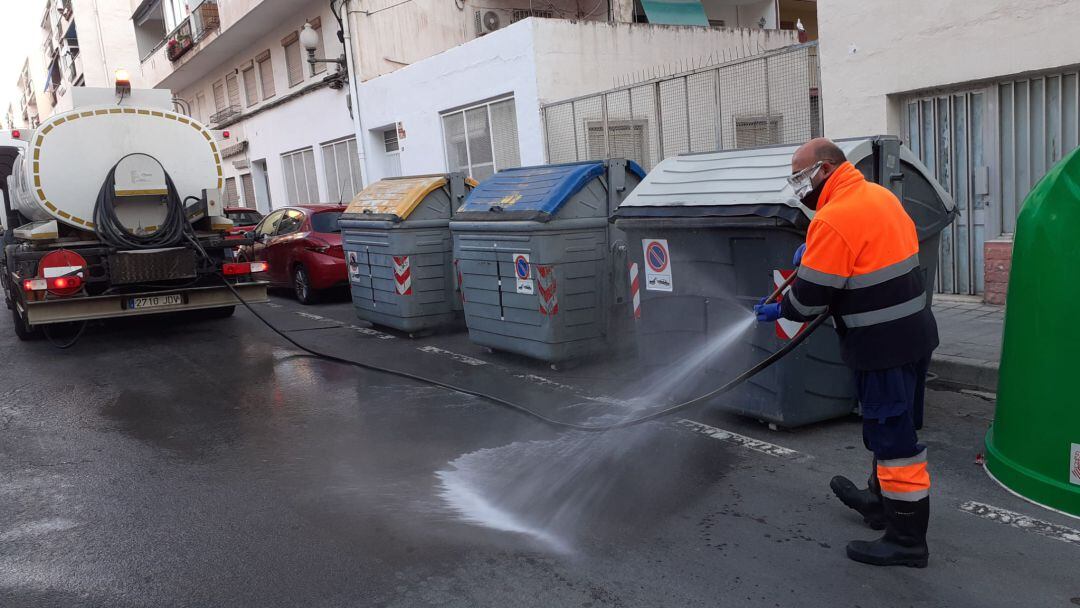 Un operario del servicio de limpieza desinfecta unos contenedores de recogida selectiva