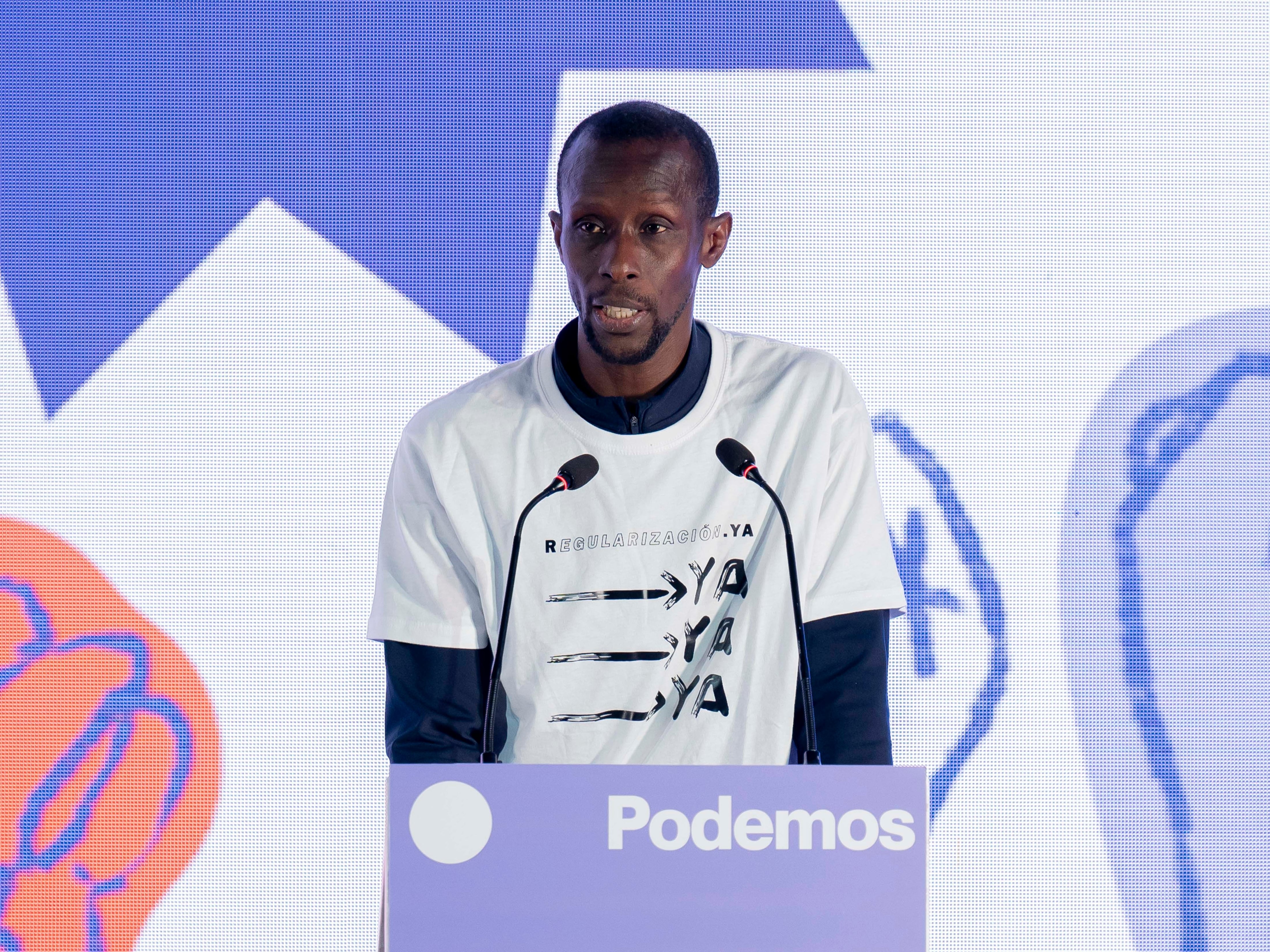 El secretario de antirracismo de Podemos, Serigne Mbaye, habla durante el evento 'Regularización son derechos'