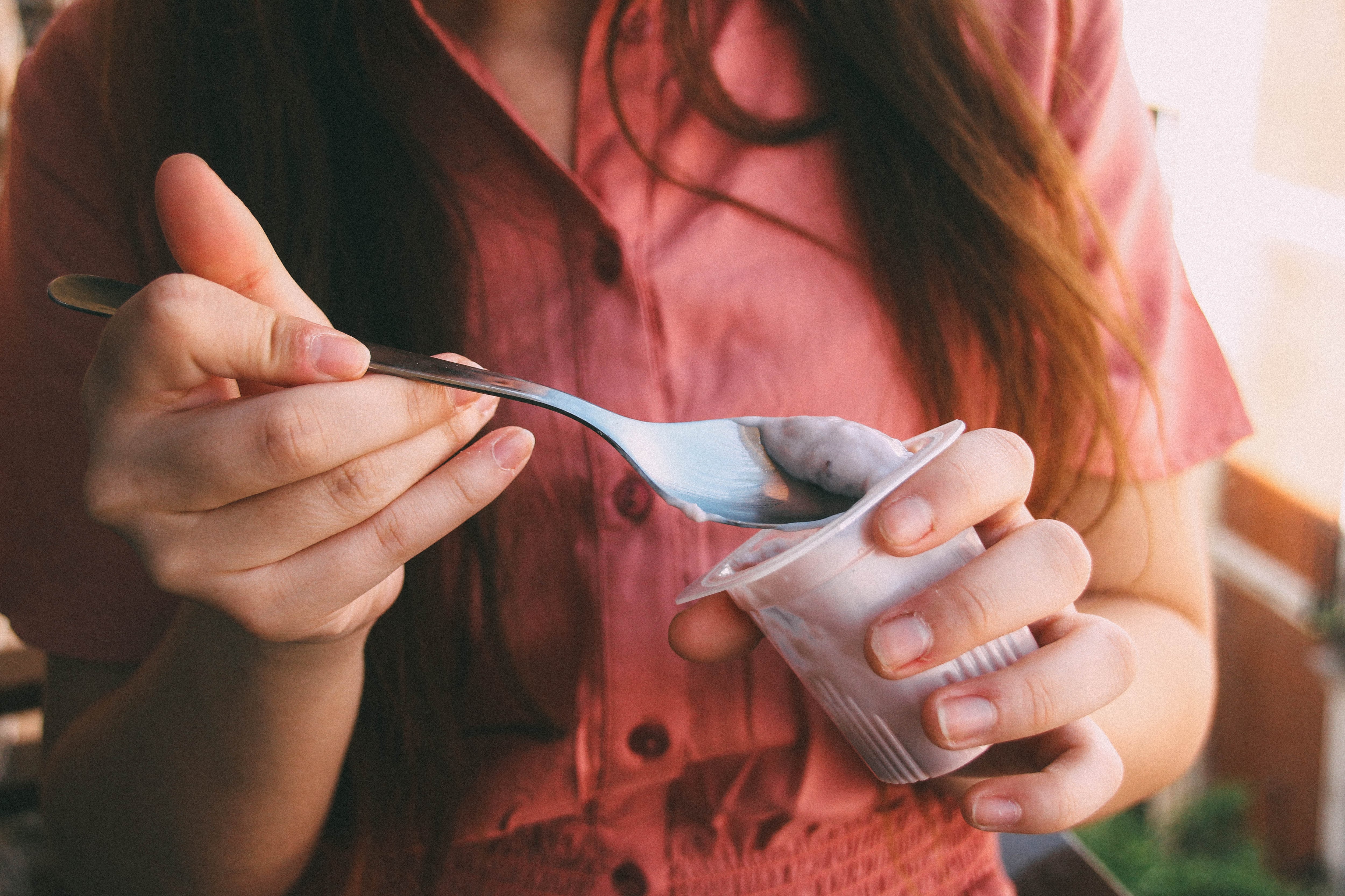 Una mujer comiéndose un yogur.