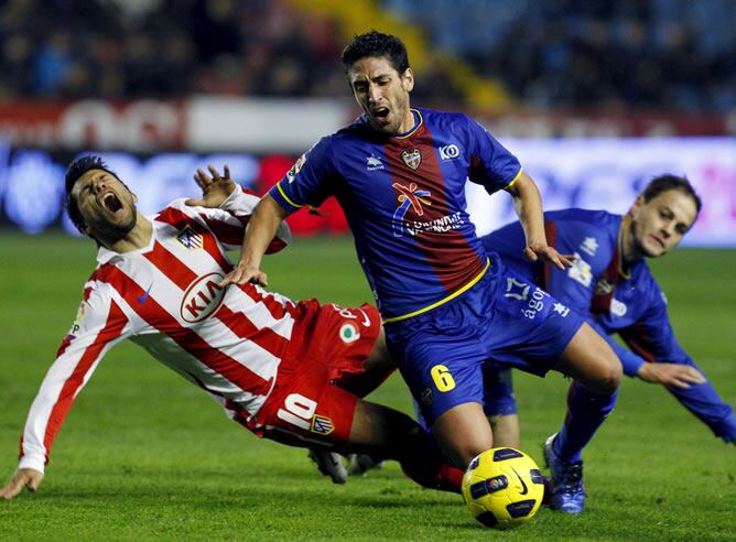 El centrocampista del Levante Miguel Pallardó (c) y el delantero argentino del Atlético de Madrid Sergio Leonel Agüero (i) caen al suelo ante el defensa del Levante Victoriano Rivas &quot;Nano