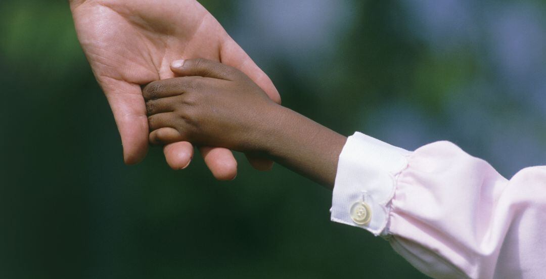 Un niño coge de la mano a un adulto.