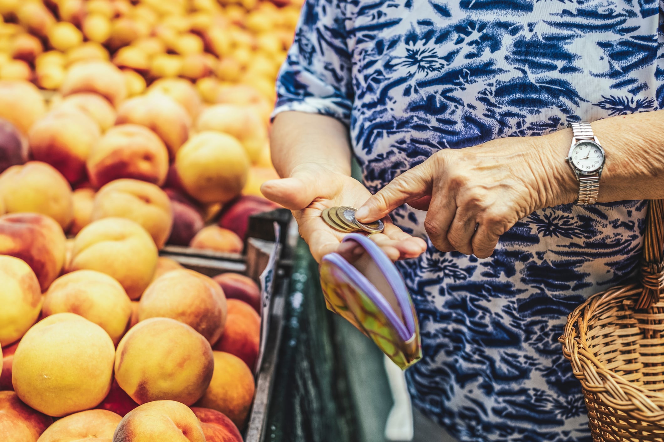 Una mujer mayor cuenta las monedas de las que dispone para poder efectuar la compra en una frutería