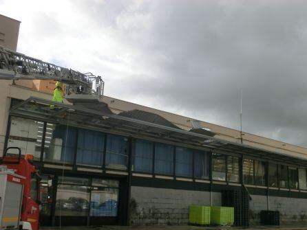 Bomberos retirando las planchas metálicas de la marquesina del edificio del Pòsit de Dénia.