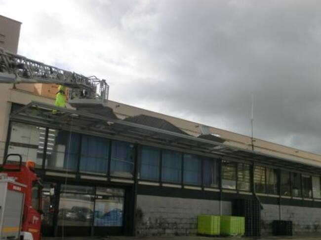 Bomberos retirando las planchas metálicas de la marquesina del edificio del Pòsit de Dénia.