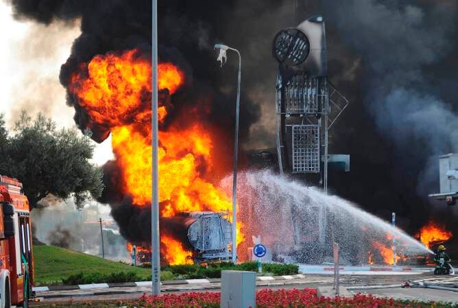 Bomberos extinguiendo un fuego israelí tras estallar un cohete en una estación de gasolina en Ashdod