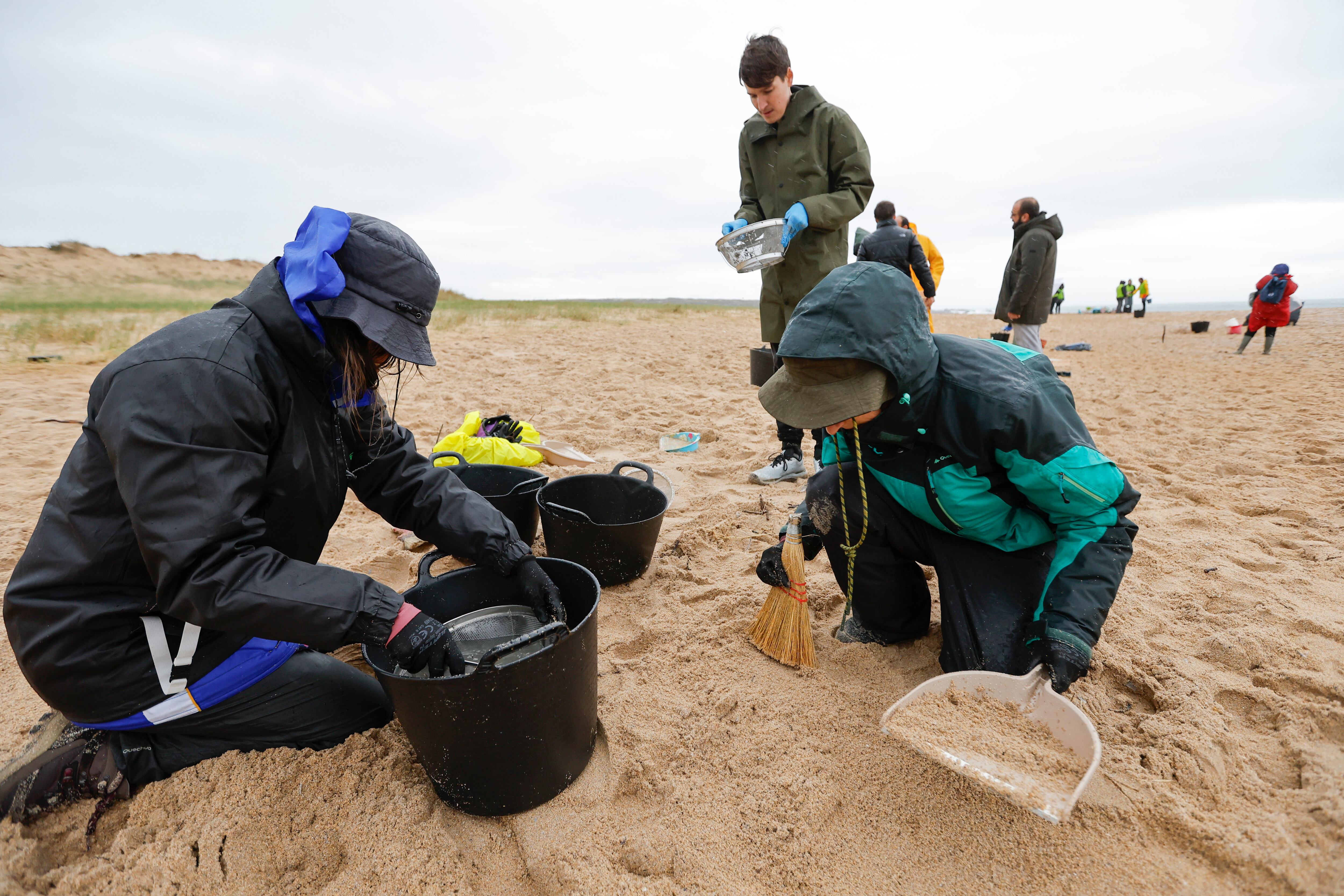 Un grupo de voluntarios recogiendo pellets en Corrubedo. EFE/Lavandeira jr