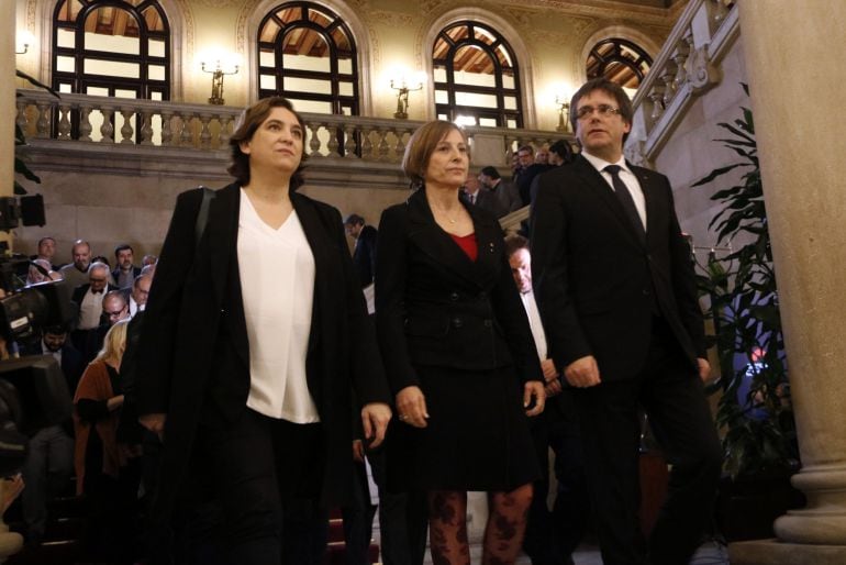 El president Carles Puigdemont baja las escaleras del Parlament junto a la presidenta, Carme Forcadell, y la alcaldesa de Barcelona, Ada Colau