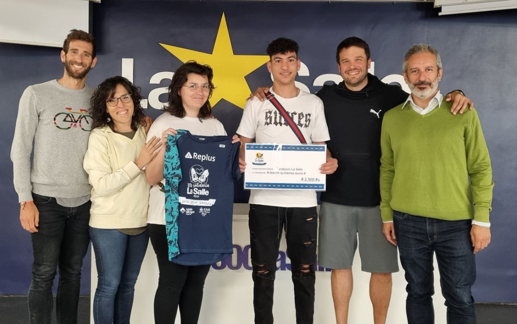 Rafa Carbonell y dos jóvenes de los pisos de emancipación de La Salle Acoge reciben el cheque de manos de profesores de La Salle