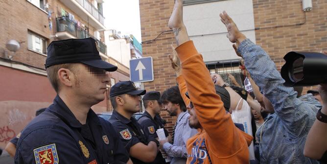 Varios policías controlan a los doscientos manifestantes convocados por el movimiento 15-M y la Plataforma de Afectados por la Hipoteca que intentaron impedir el desahucio de una mujer