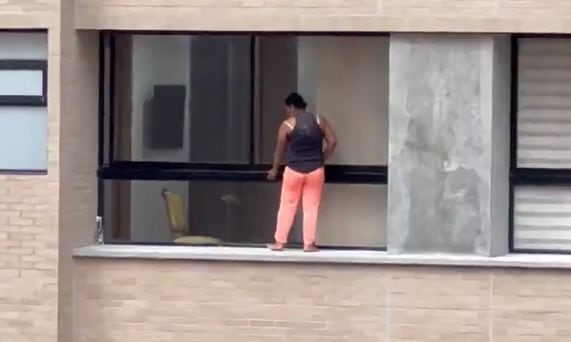 Una mujer limpia las ventanas por fuera, sin protección, en un duodécimo piso en Medellín (Colombia).