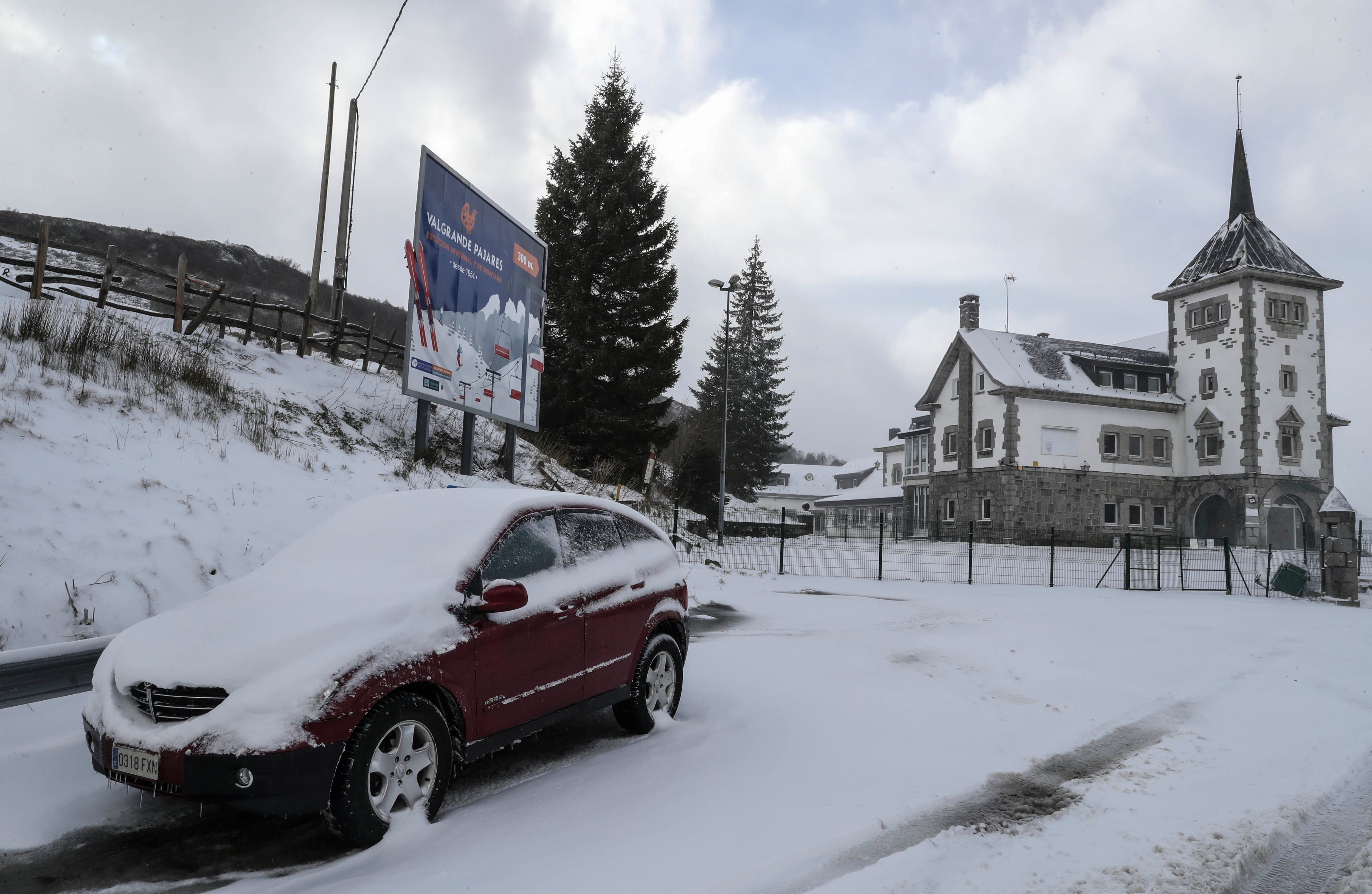 Un coche permanece estacionado en el alto del Puerto de Pajares (Asturias), donde las máquinas quitanieves trabajan intensamente
