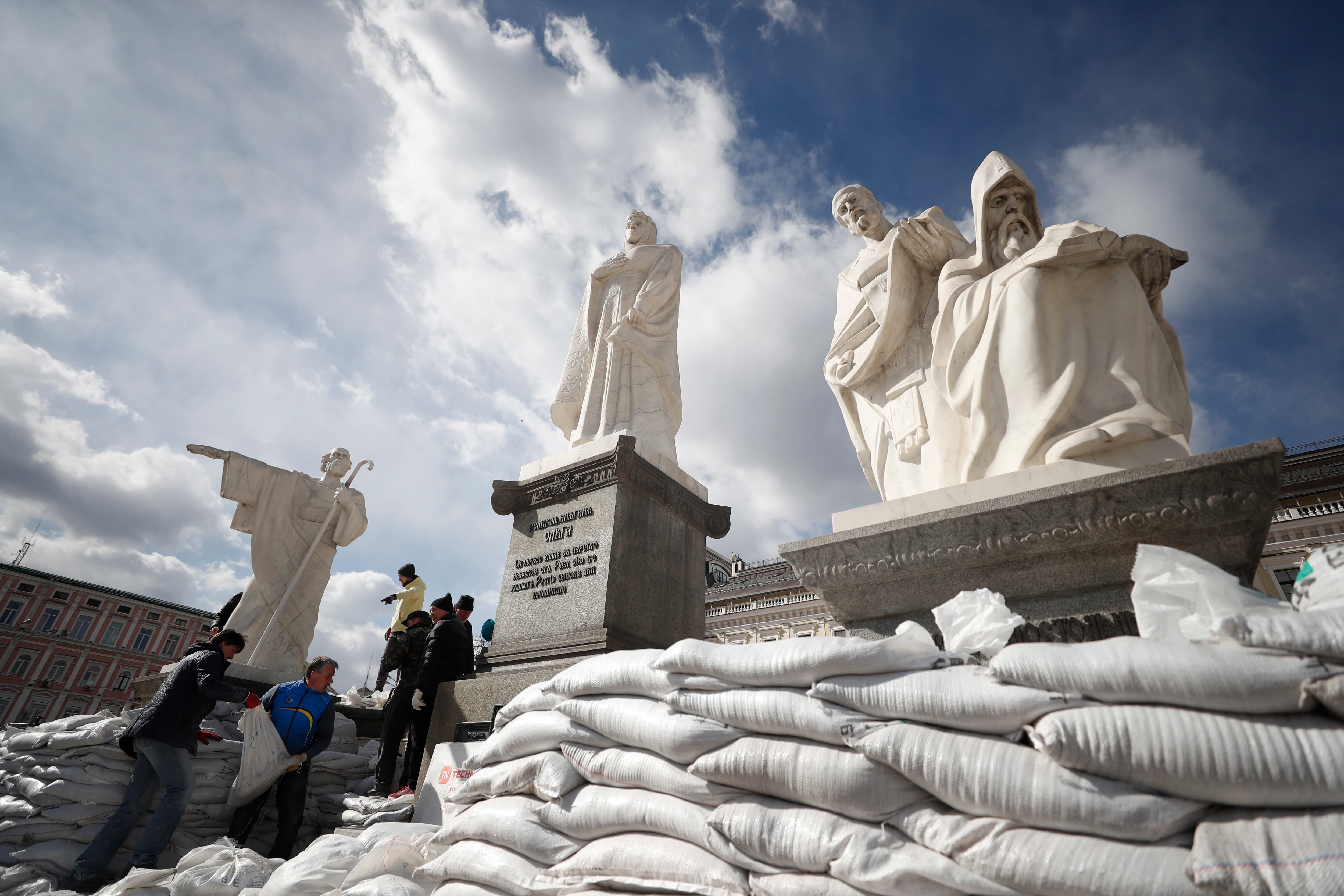 Varios voluntarios cubren con sacos de arena el Monumento a la Princesa Olga, el Apóstol Andrés, y los santos Cirilo y Metodio para protegerlos de los bombardeos rusos, en la capital ucraniana de Kiev,