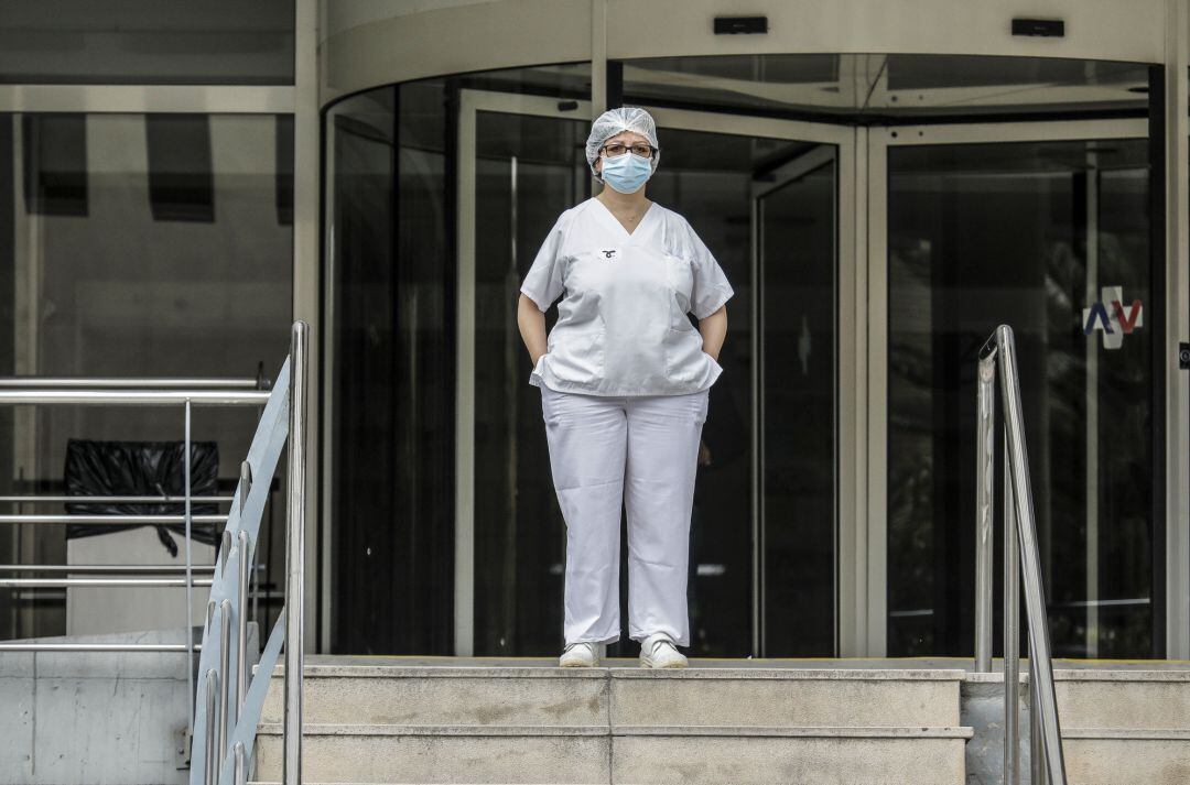 Sanitaria protegida con mascarilla y gorro durante el minuto de silencio en la entrada del Hospital Doctor Peset por la técnica de enfermería fallecida por coronavirus, en Valencia