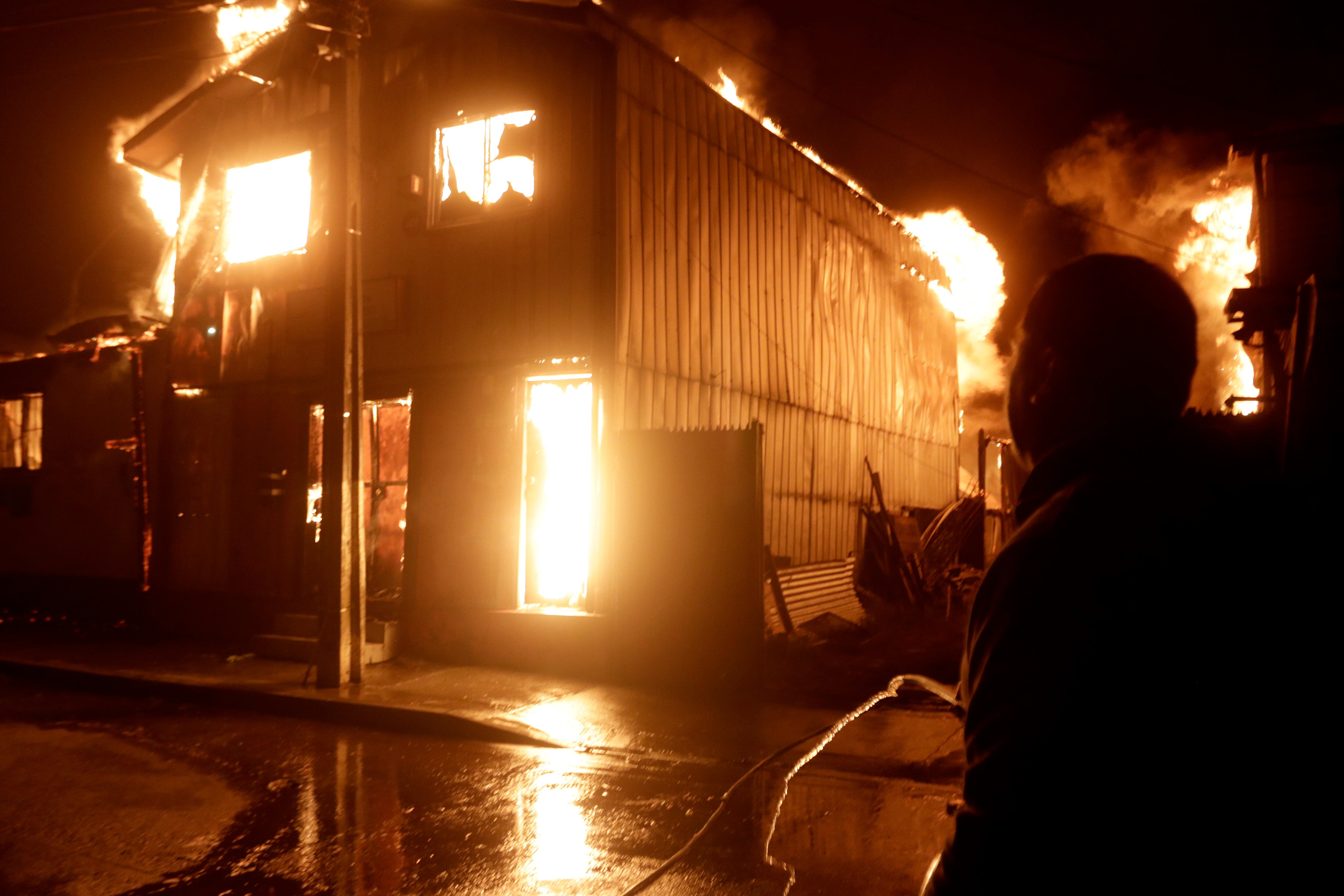 AME6365. PENCO (CHILE), 18/01/2026.- Una persona observa casas afectadas por los incendios forestales la madrugada de este domingo, en Penco (Chile). EFE/ Patricio Aguayo