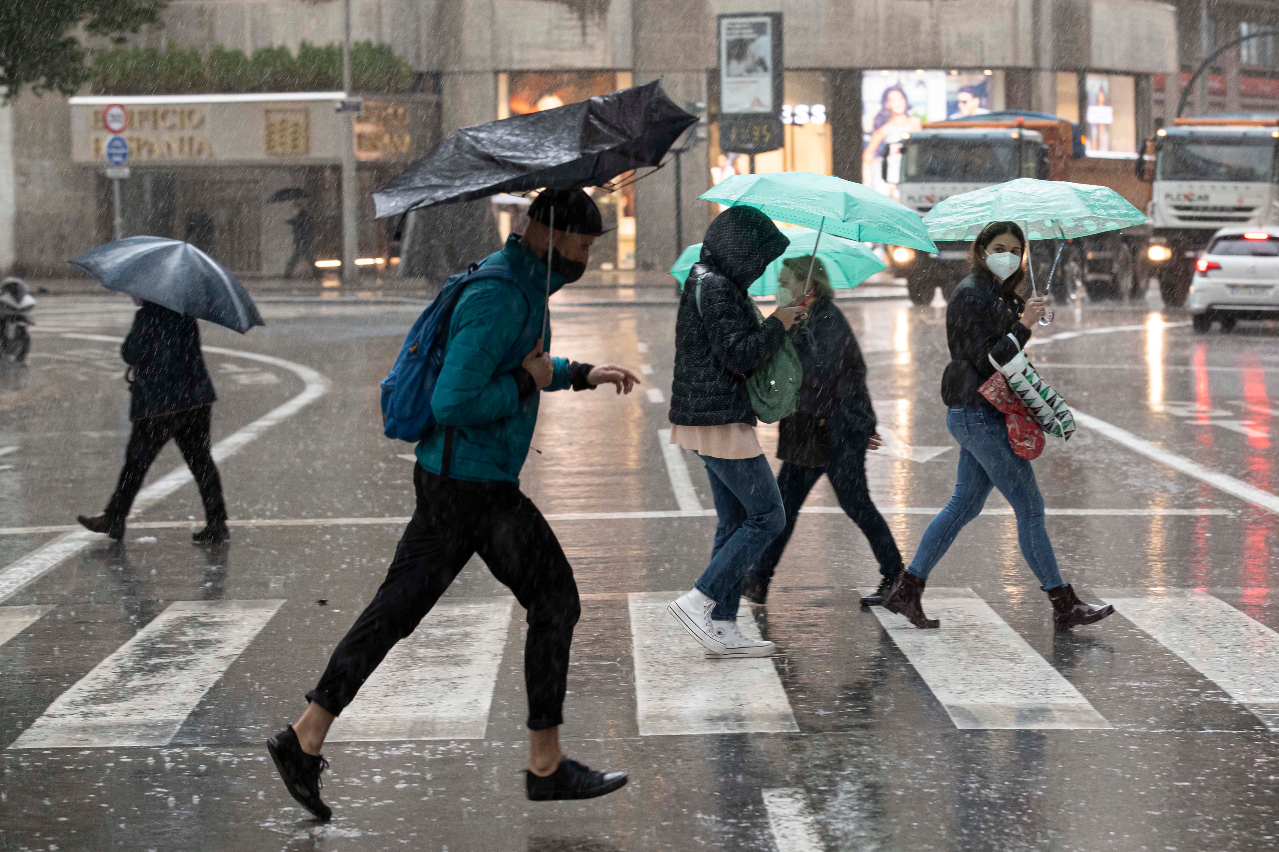 Varias personas se resguardan de la lluvia en la Gran Vía de Murcia