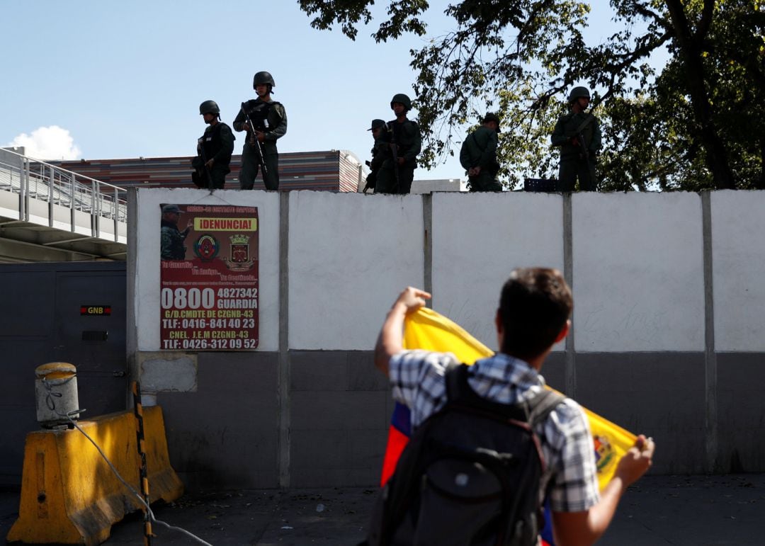 Seguidores de Juan Guaidó sostienen banderas de Venezuela frente a un cuartel militar