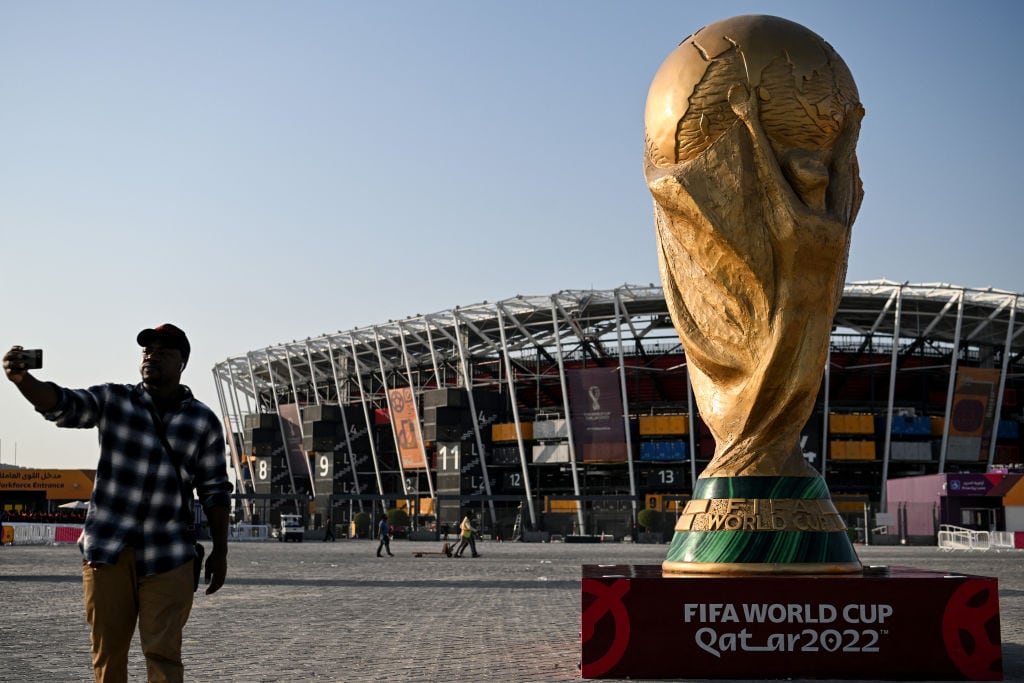 Un aficionado se toma una foto con una réplica de la Copa del Mundo.