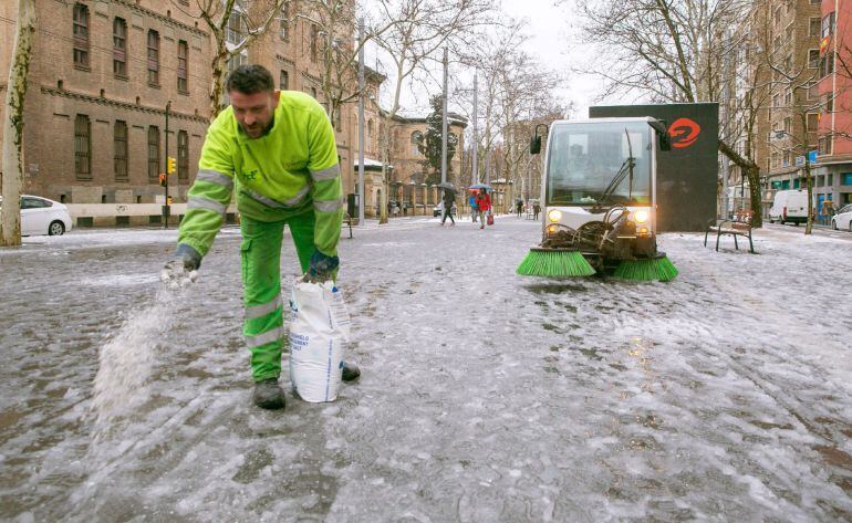 Un operario esparce sal por las calles de Zaragoza, que ha despertado con las calles cubiertas de nieve