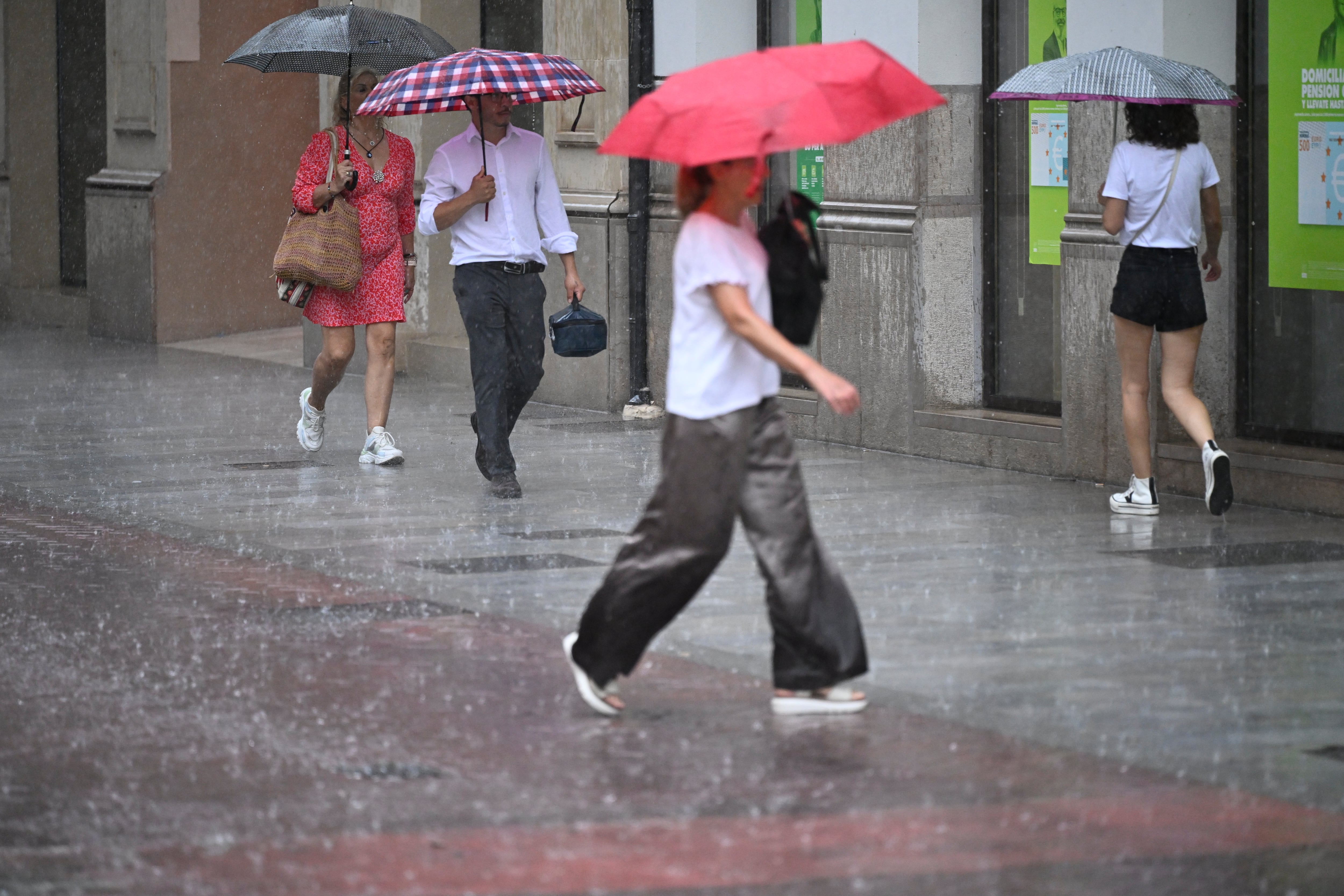 FOTODELDÍA GRAFCVA8549. CASTELLÓN, 09/07/2025.- Varias personas caminan, este miércoles, por una calle de la ciudad de Castellón bajo una intensa lluvia. La Agencia Estatal de Meteorología (Aemet) ha establecido para la mañana de este miércoles el aviso naranja en el litoral sur de Castellón por precipitaciones de 40 litros por metro cuadrado en una hora acompañadas de actividad eléctrica. EFE/Andreu Esteban
