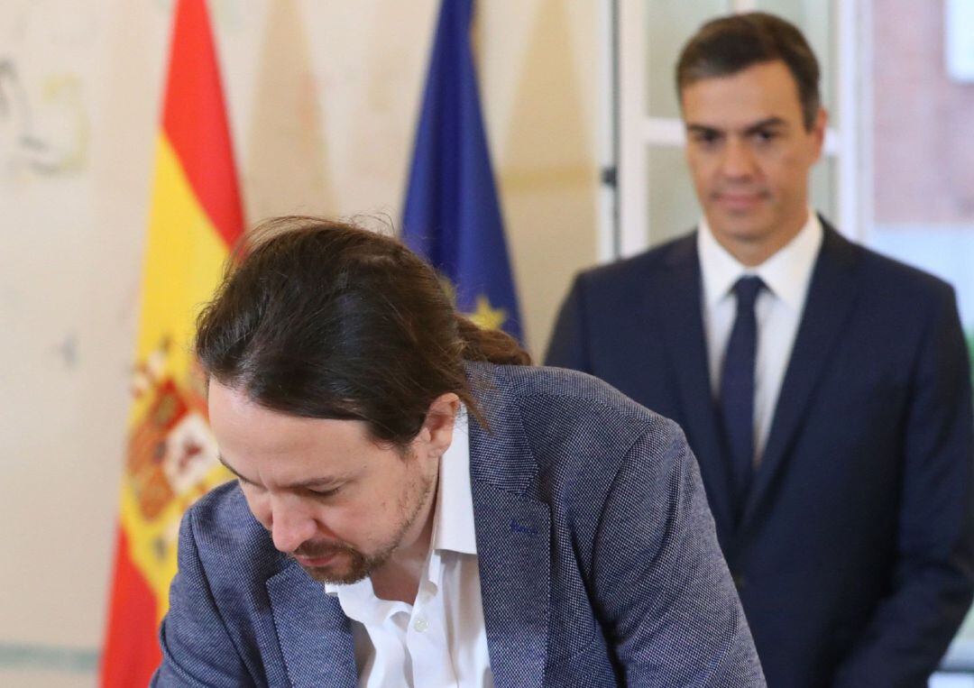 El presidente del Gobierno, Pedro Sánchez (fondo), y el secretario general de Podemos, Pablo Iglesias, han firmado hoy en el Palacio de la Moncloa el acuerdo sobre el proyecto de ley de presupuestos para 2019.