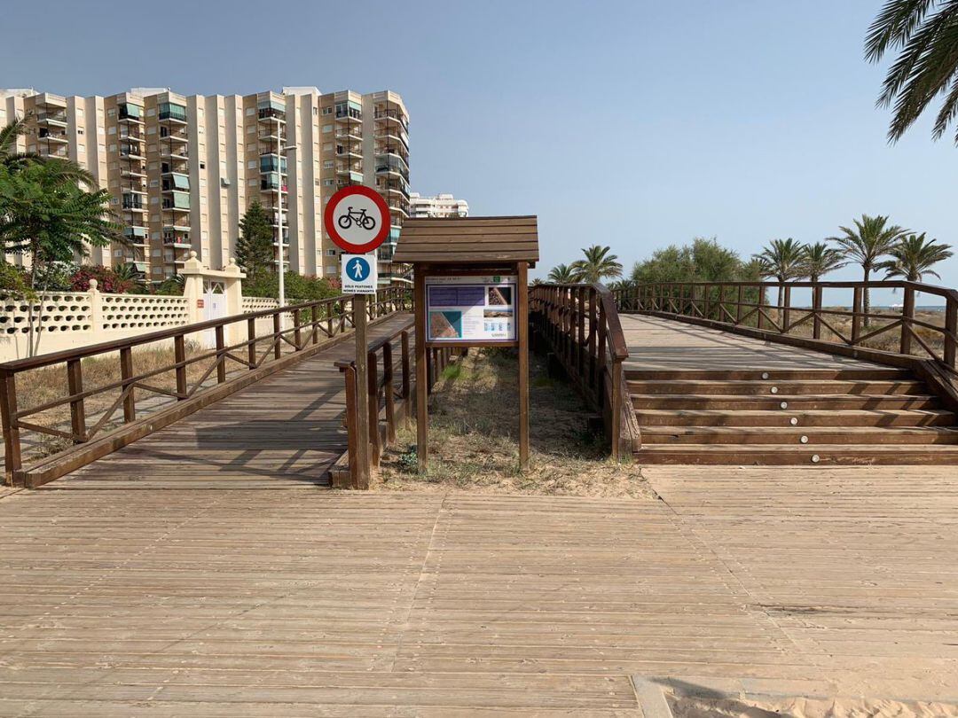 Pasarela de madera al final de la playa con las señales de prohibición. 