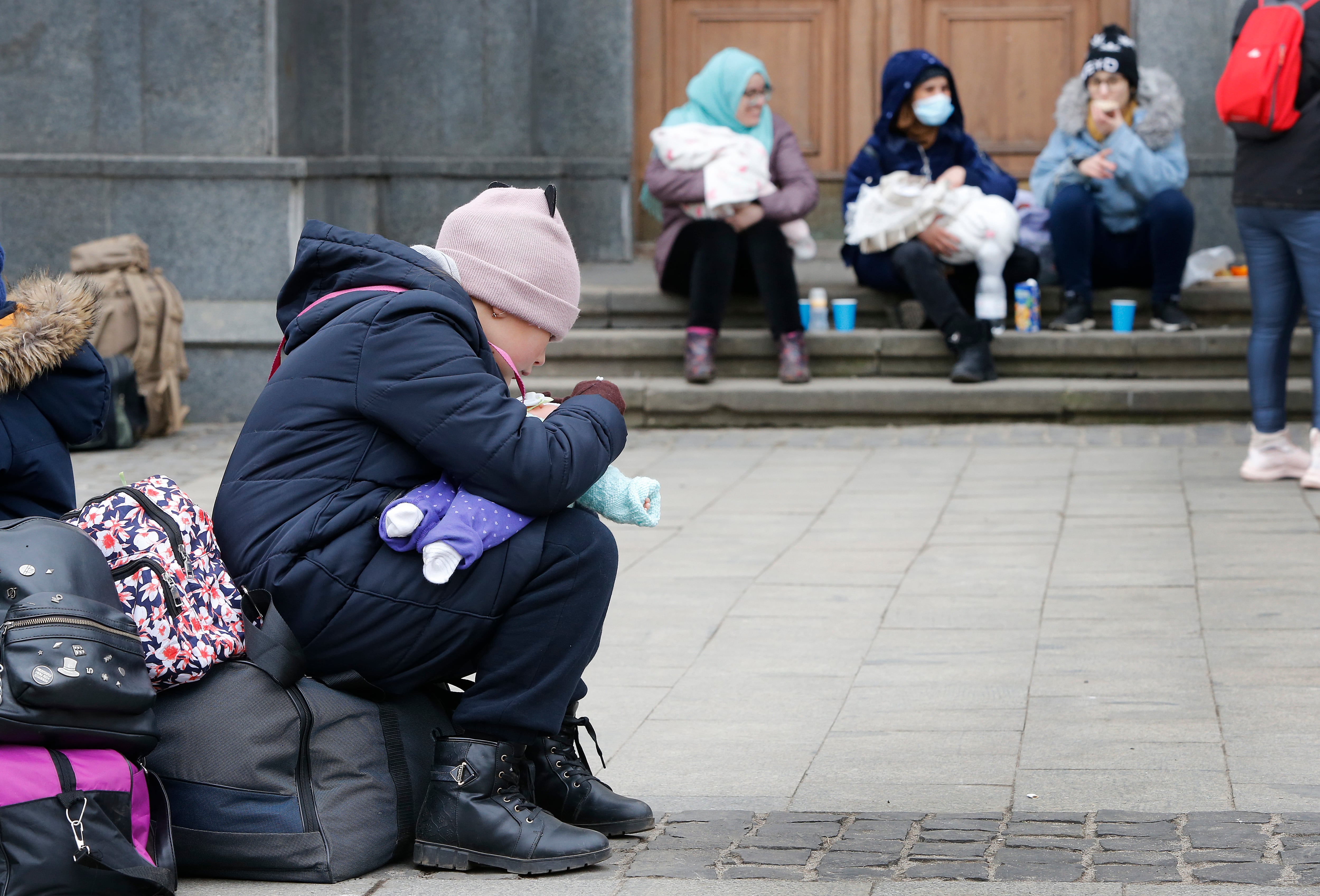 Una niña juega con su muñeca en la ciudad de Lviv este miércoles, mientras miles de refugiados entran y salen de la estación intentando huir de Ucrania hacia Polonia y de los bombardeos de Kiev. EFE/Manuel Lorenzo