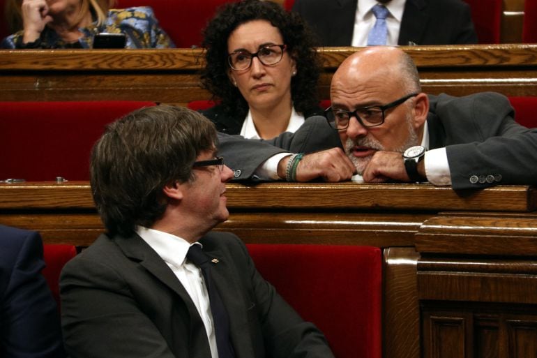 Carles Puigdemont, conversando con Lluís Corominas frente a Marta Rovira, en el Parlament de Catalunya, en 2017.