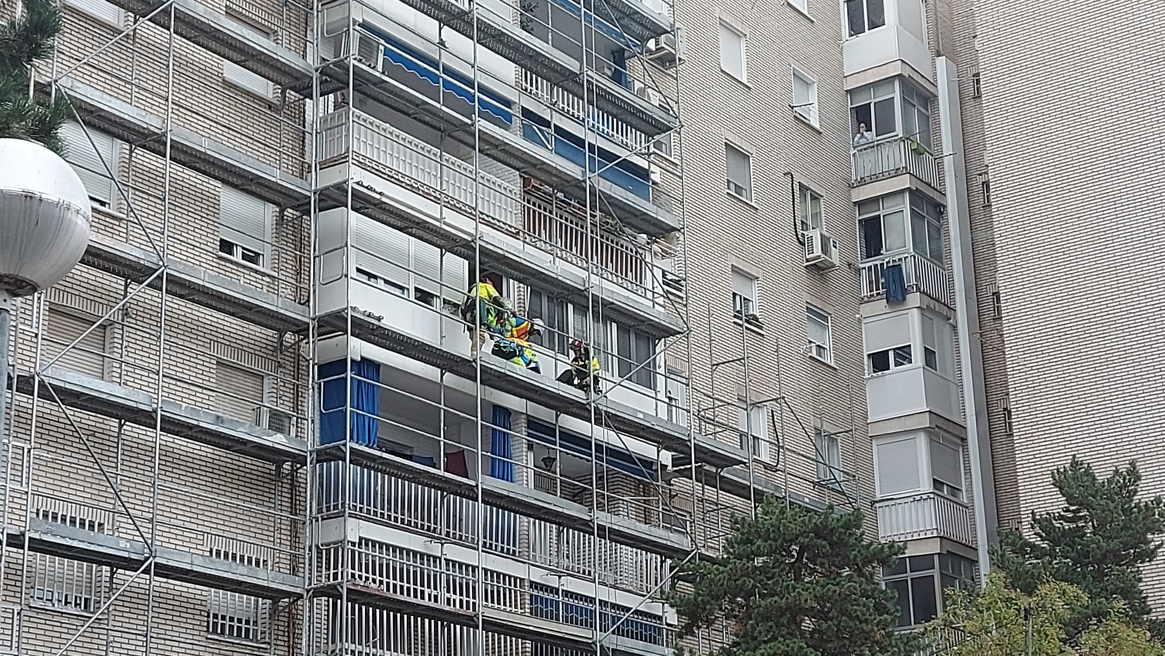 Los bomberos y sanitarios atendiendo al herido en el andamio