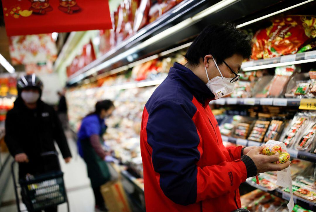 Personas en China comprando alimentos con mascarillas.