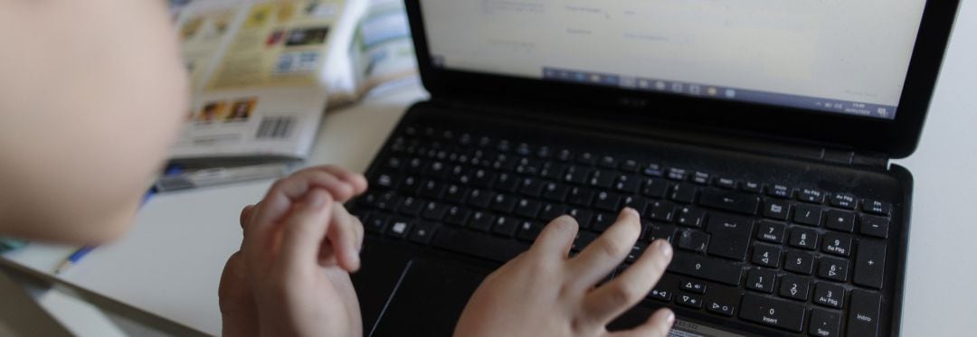 Un alumno de primaria hace los deberes de la asignatura de Inglés con varios libros y un ordenador, foto de archivo