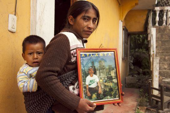 Una mujer sostiene la fotografía de su marido que acaba de emigrar a Estados Unidos.