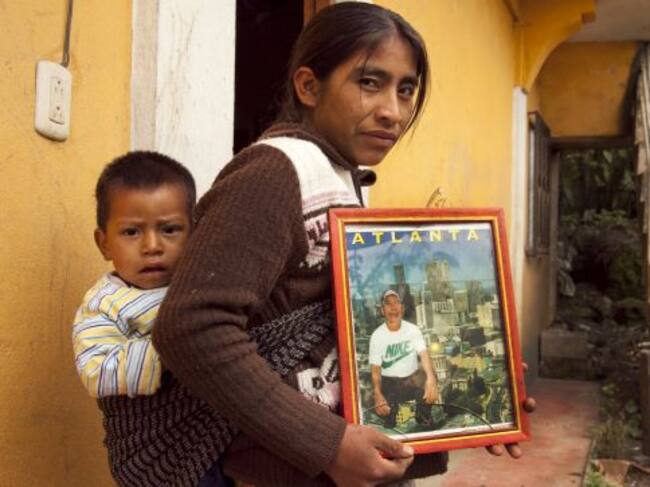 Una mujer sostiene la fotografía de su marido que acaba de emigrar a Estados Unidos.