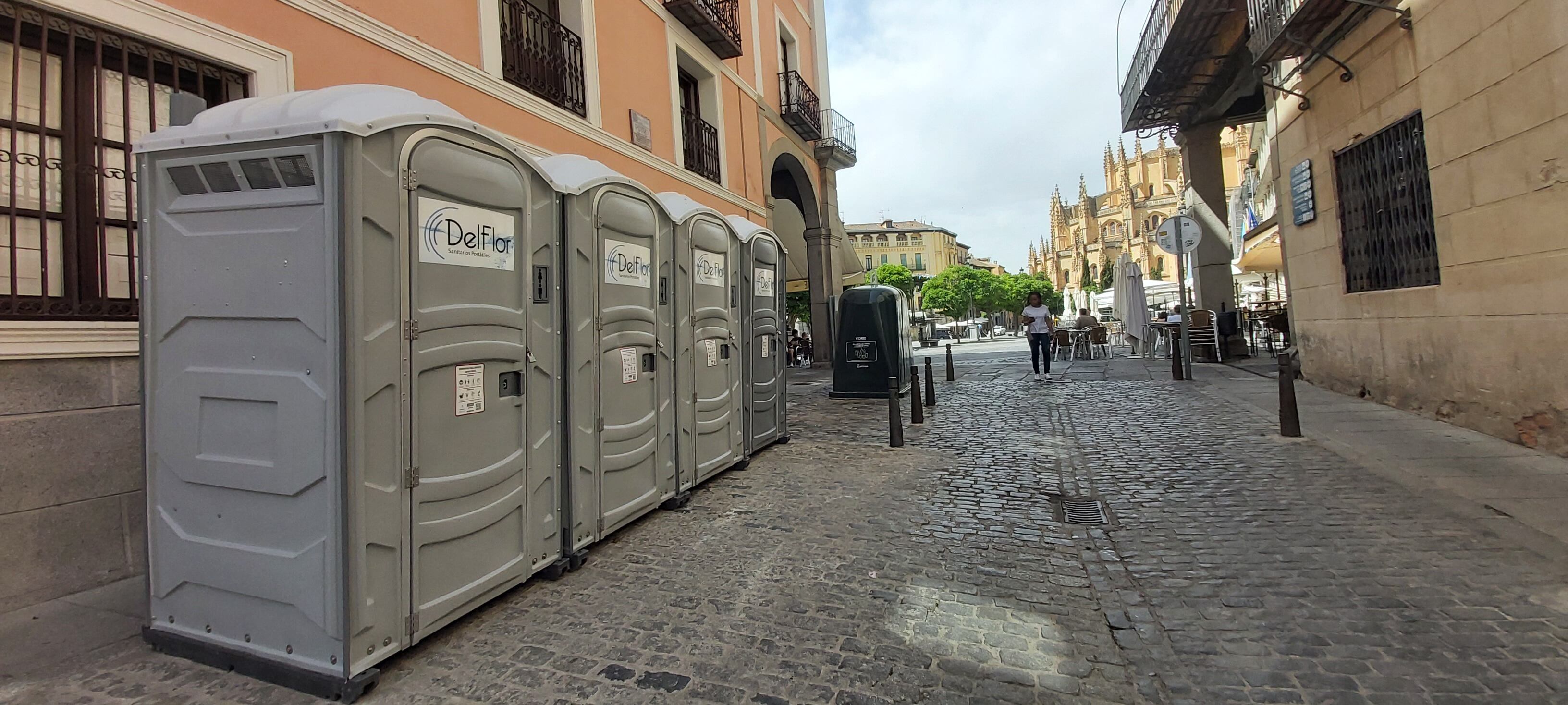 Urinarios Portátiles instalados en las inmediaciones de la Plaza Mayor de Segovia y al fondo un contenedor de vidrio.