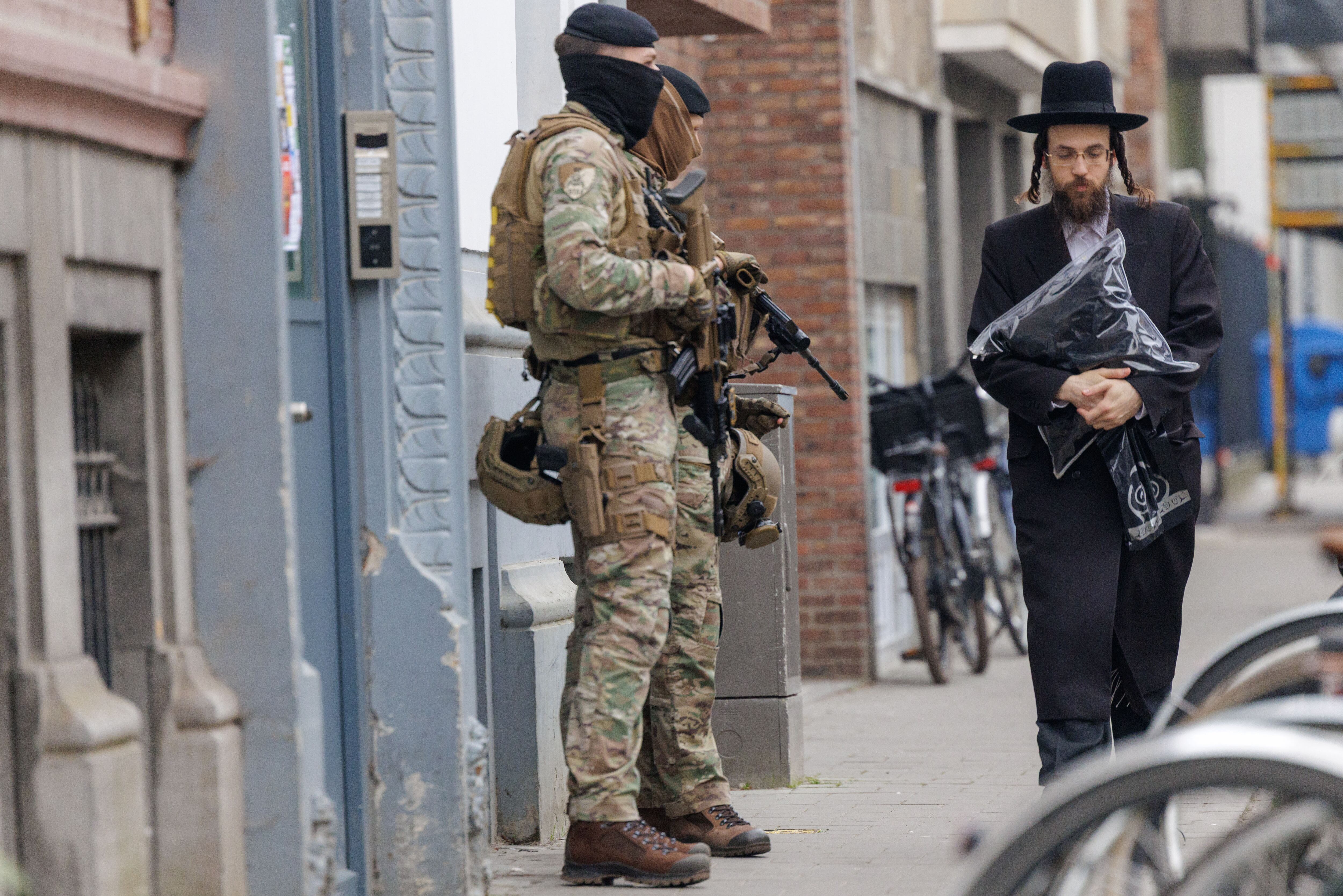 Antwerp (Belgium), 24/03/2026.- A member of the Jewish community walks past Belgian soldiers guarding a Jewish site amid rising antisemitic terror threats in Antwerp, Belgium, 24 March 2026. The Belgian government announced on 16 March that it will deploy military personnel to reinforce the Federal Police to protect a number of synagogues and Jewish schools across the country following a series of antisemitic attacks in Europe. (Bélgica, Amberes) EFE/EPA/OLIVIER MATTHYS