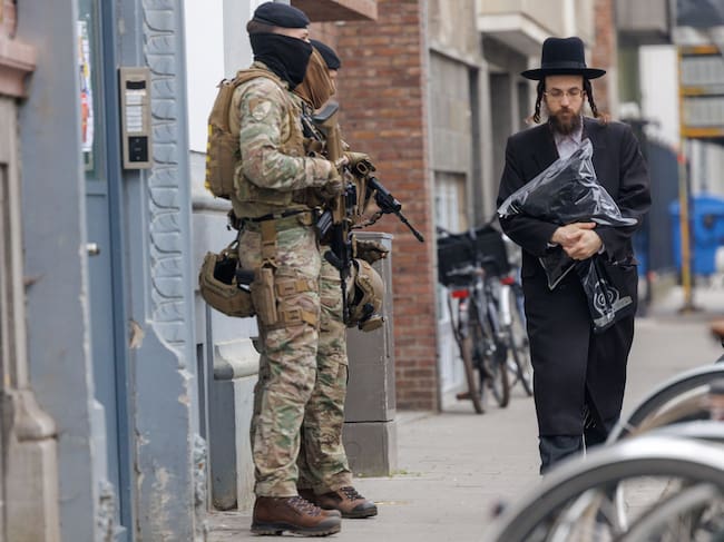 Antwerp (Belgium), 24/03/2026.- A member of the Jewish community walks past Belgian soldiers guarding a Jewish site amid rising antisemitic terror threats in Antwerp, Belgium, 24 March 2026. The Belgian government announced on 16 March that it will deploy military personnel to reinforce the Federal Police to protect a number of synagogues and Jewish schools across the country following a series of antisemitic attacks in Europe. (Bélgica, Amberes) EFE/EPA/OLIVIER MATTHYS