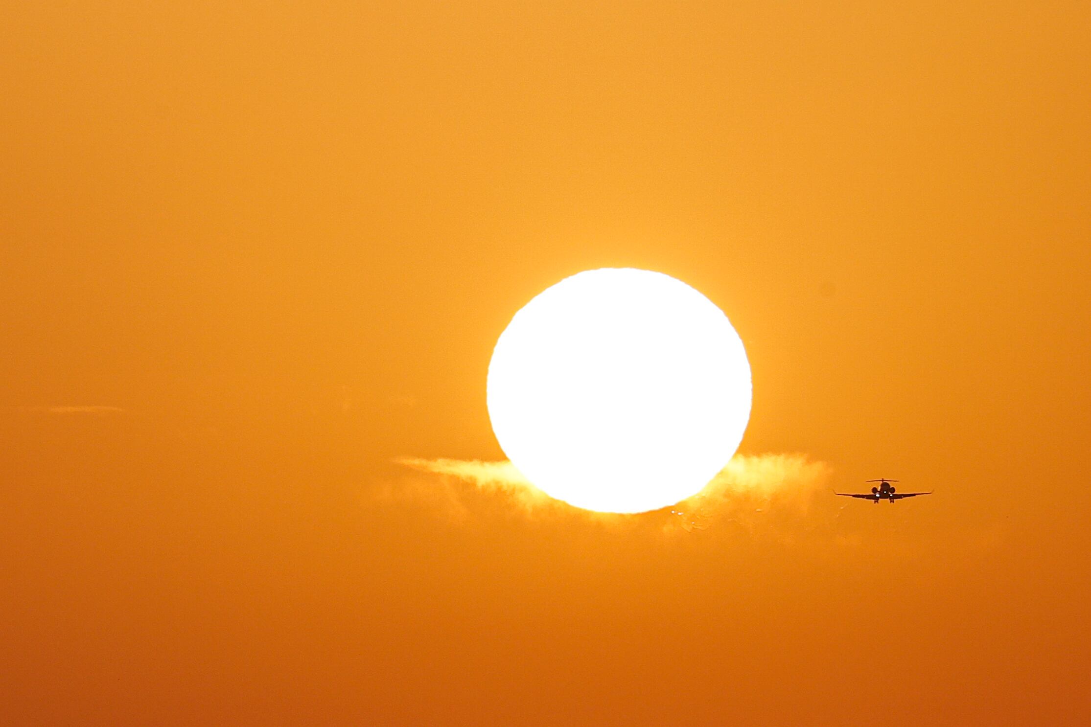Un avión se aproxima al aeropuerto de Manises en Valencia a última hora de la tarde de este domingo durante la puesta del sol
