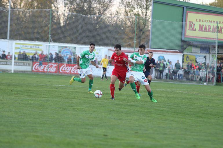 Javier Orodea se lleva el balón ante los defensas del At. Astorga