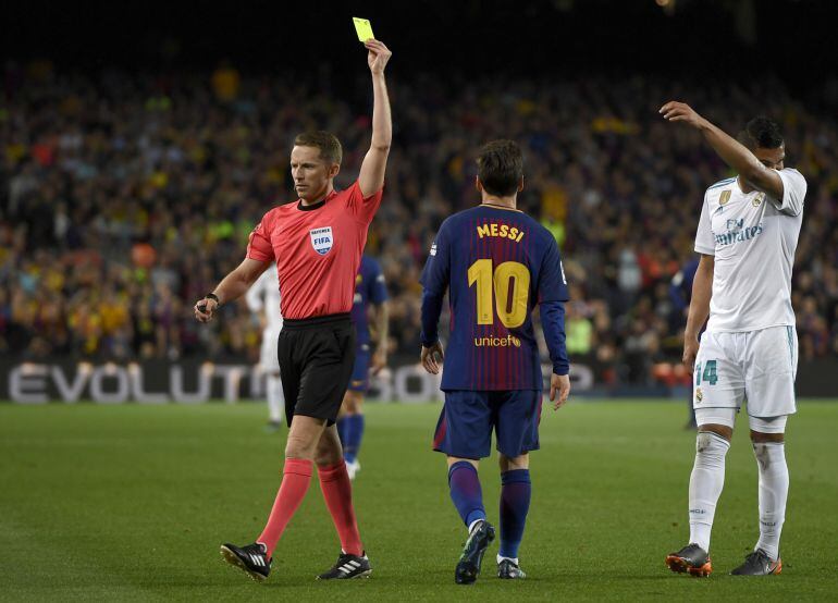 Hernández Hernández le pone una amarilla a Messi durante el Clásico. 