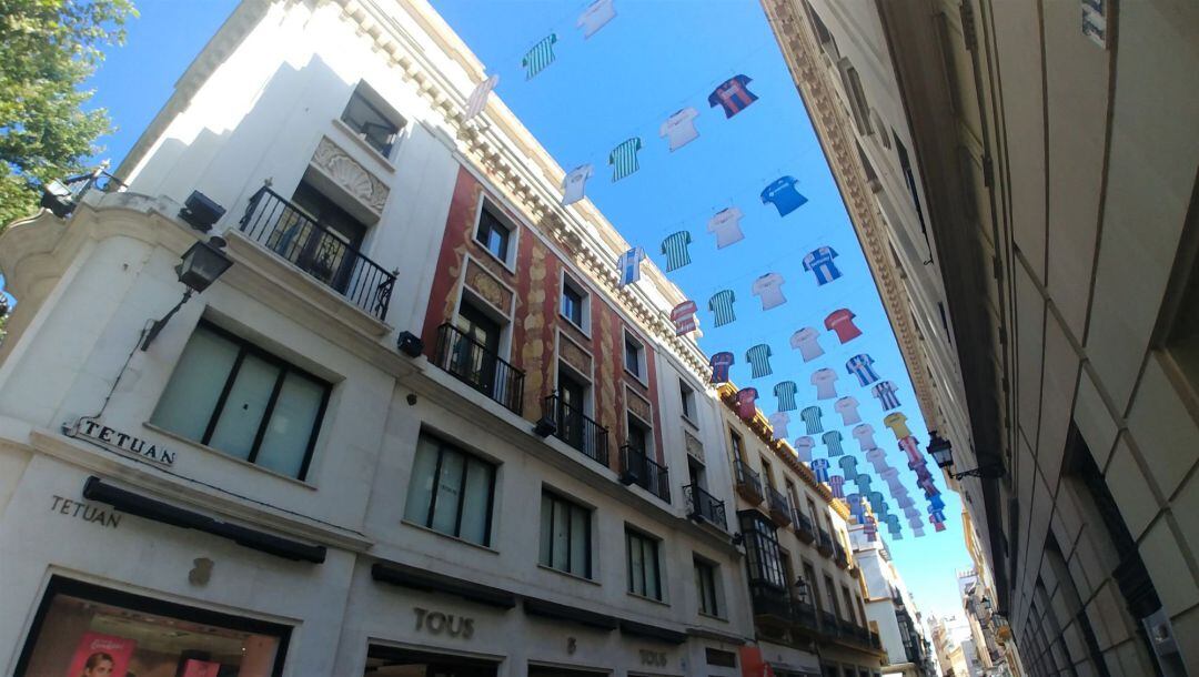 SEV05. SEVILLA.- Imagen de la calle Tetuán en el centro de Sevilla, una de las arterias comerciales principales, que ha amanecido adornada con más de medio centenar de camisetas de los equipos de laLiga con las que se ha dado este lunes la bienvenida a la vuelta del fútbol después de tres meses de parón con uno de los clásicos de mayor rivalidad del universo futbolero, el Sevilla-Betis del próximo jueves en el Ramón Sánchez Pizjuán (22.00 horas).EFE Juan de Lara