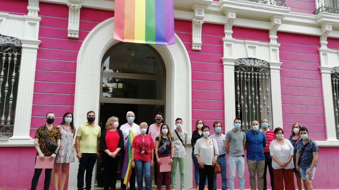 Asistentes a la lectura del manifiesto y miembros de la corporación posan ante el museo Cristina García Rodero bajo la bandera arcoiris