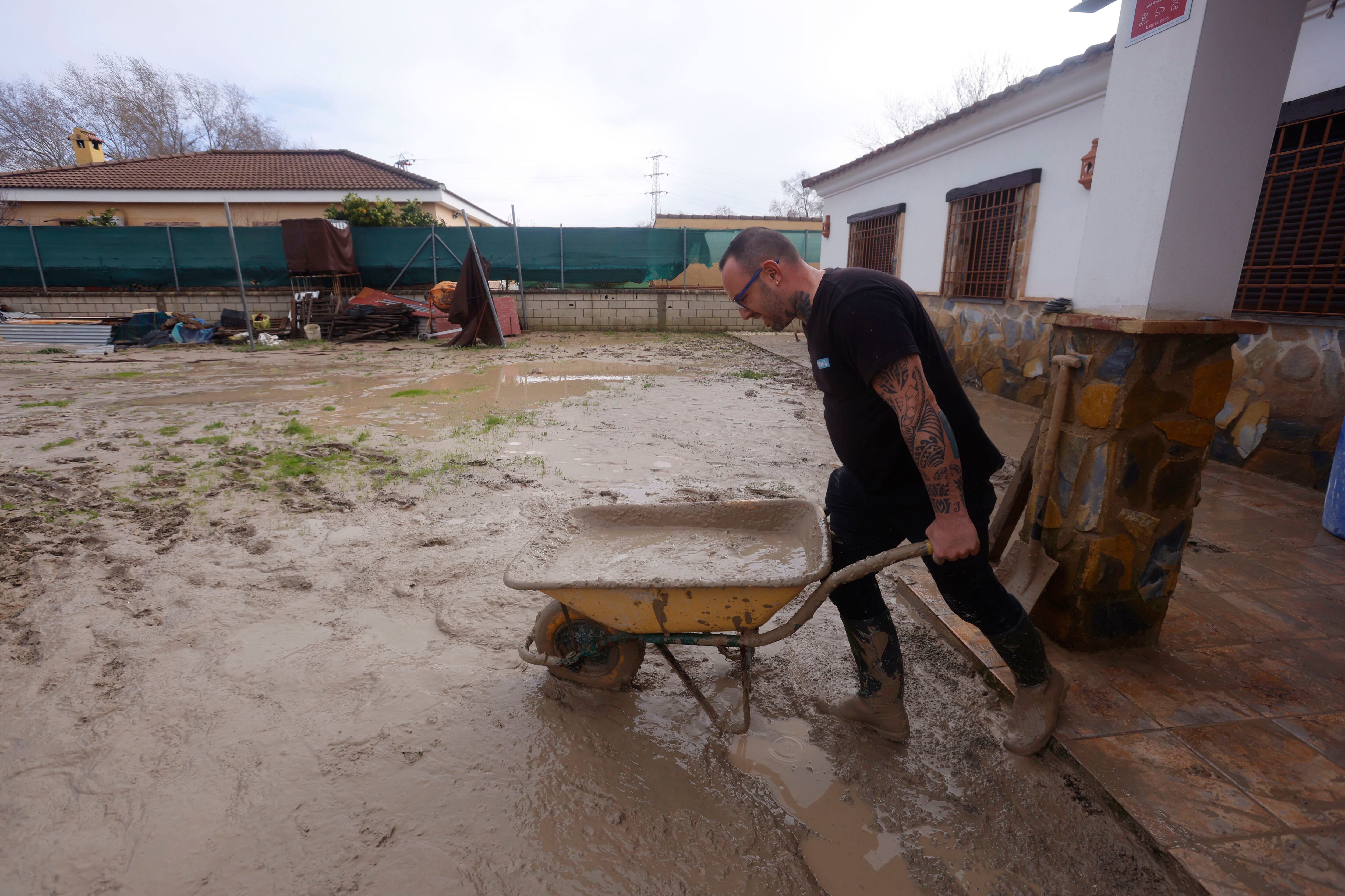 Vecinos de las parcelas próximas al río Guadalquivir, en Córdoba, que fueron desalojados a causa de las lluvias, limpian el lodo acumulado a su regreso a sus viviendas 