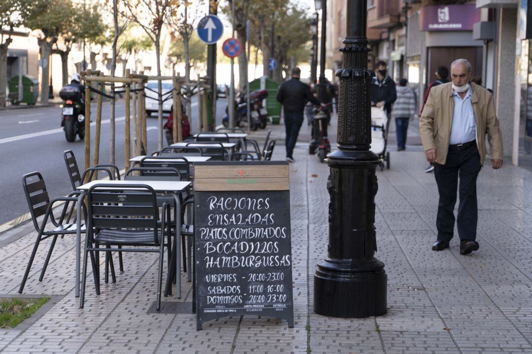 Un hombre camina frente a la terraza de un bar vacío