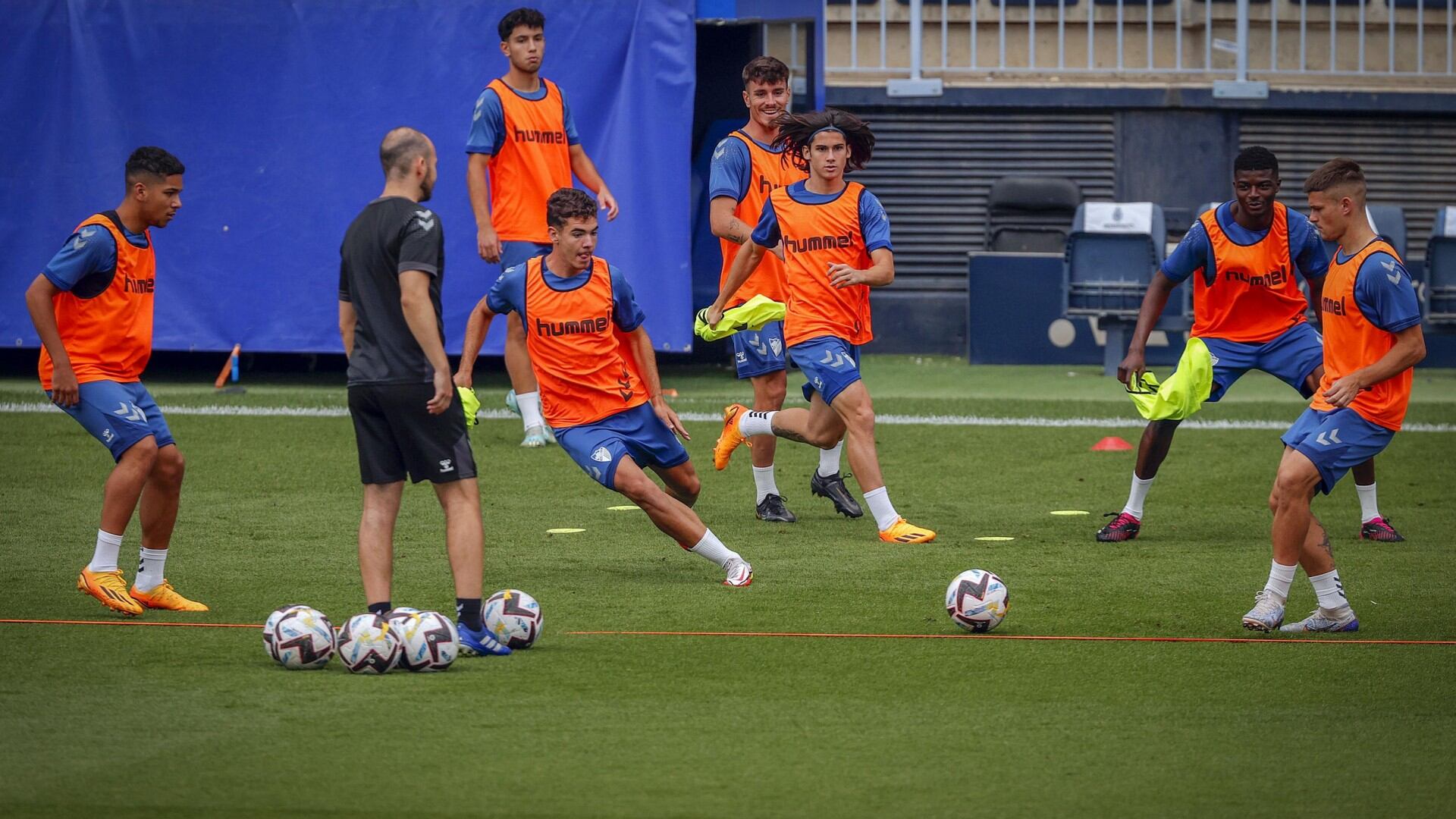 Varios canteranos del Málaga realizan un rondo en el césped de La Rosaleda