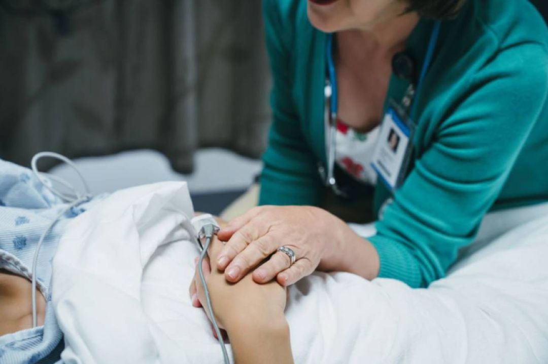 Una profesional sanitaria acompaña a un paciente de hospital