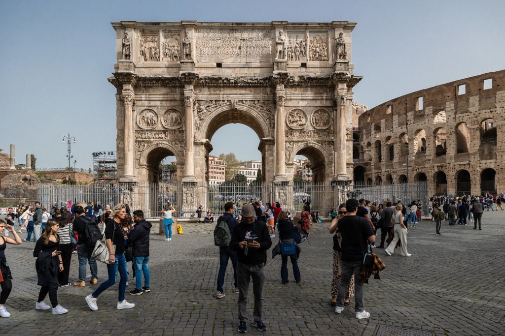 Turistas junto al Arco de Constantino y el coliseo romanos.