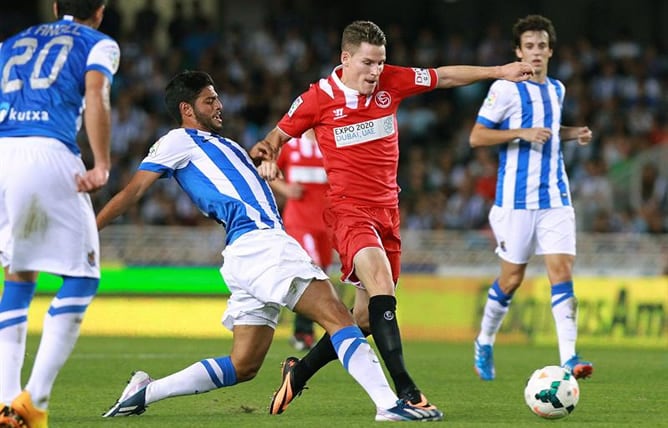 El delantero francés del Sevilla Kevin Gameiro trata de escapar del mexicano Carlos Vela, de la Real Sociedad, durante el partido correspondiente a la séptima jornada de Liga en Primera División.