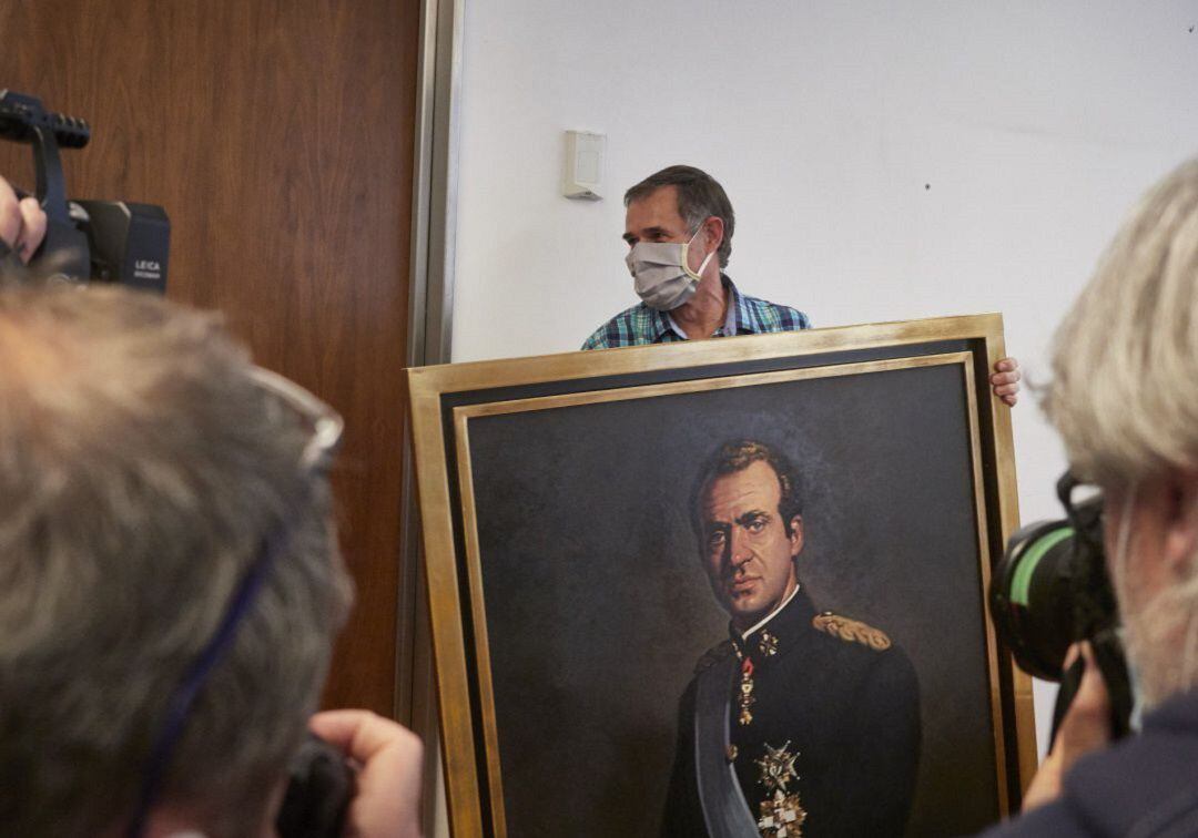 Varios fotógrafos captan el momento en que un operario retira del retrato del rey emérito Juan Carlos I de la Sala de Gobierno del Legislativo foral del Parlamento de Navarra